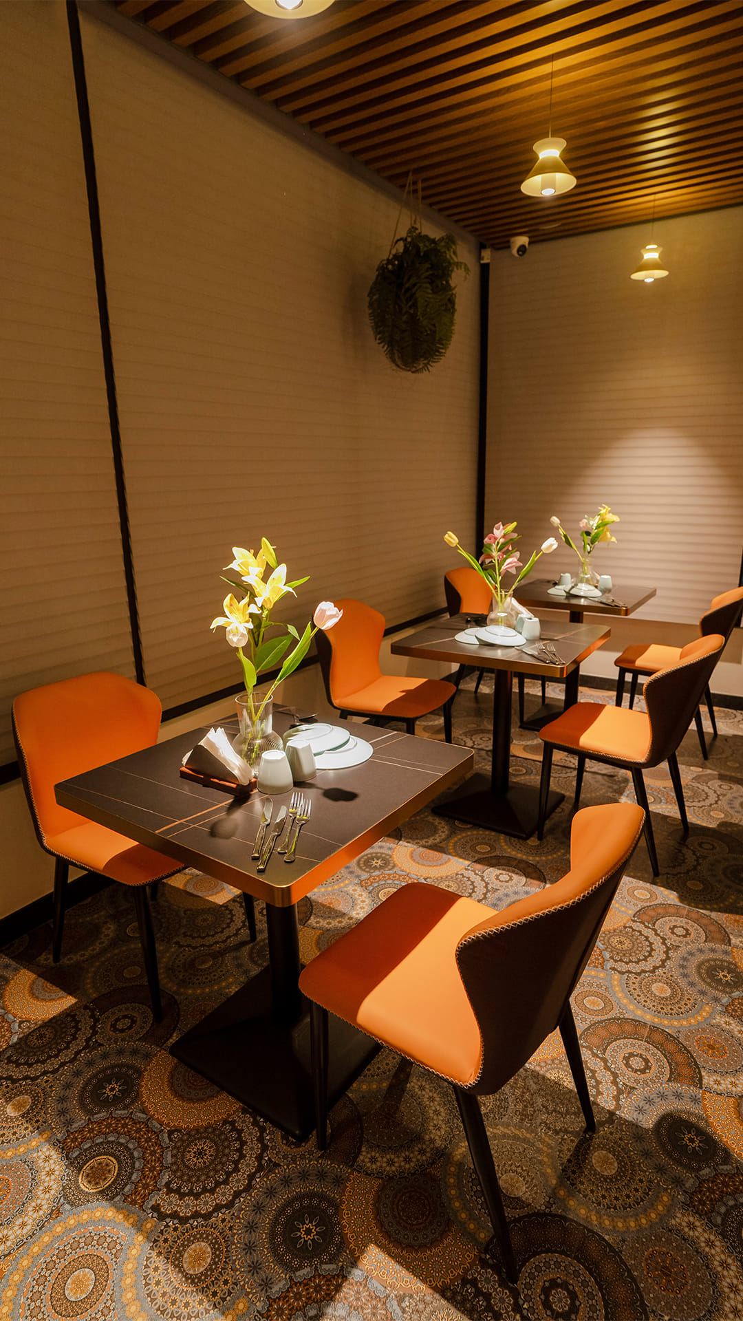 Dining alcove with pleated blinds, a hanging fern, and tables set with flowers