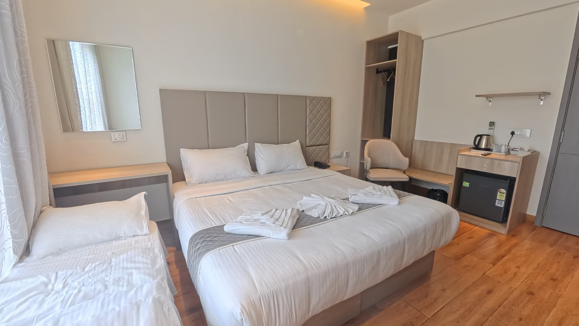 Royal King Room with a king bed, an additional single bed, and open wardrobe shelving