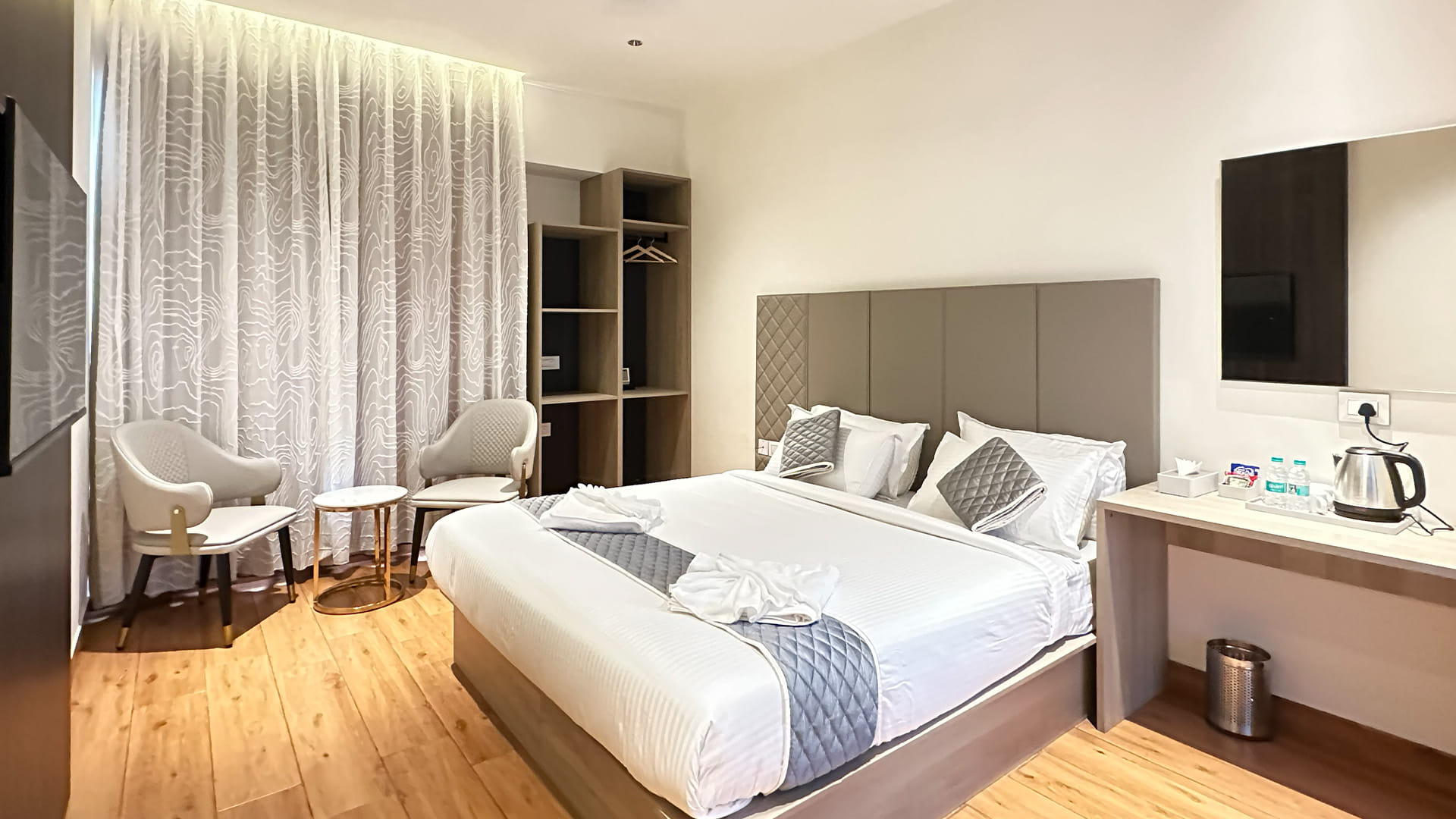 Royal King Room at Hotel Ritvi's Elite with the king bed facing a wall-mounted television and open wardrobe