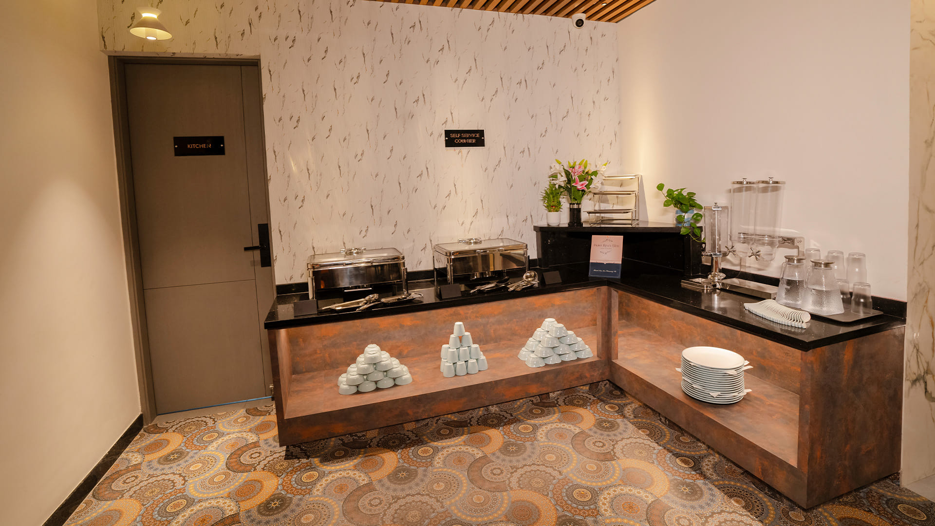 Self-service breakfast counter by the kitchen door, with flowers, glasses, and dispensers