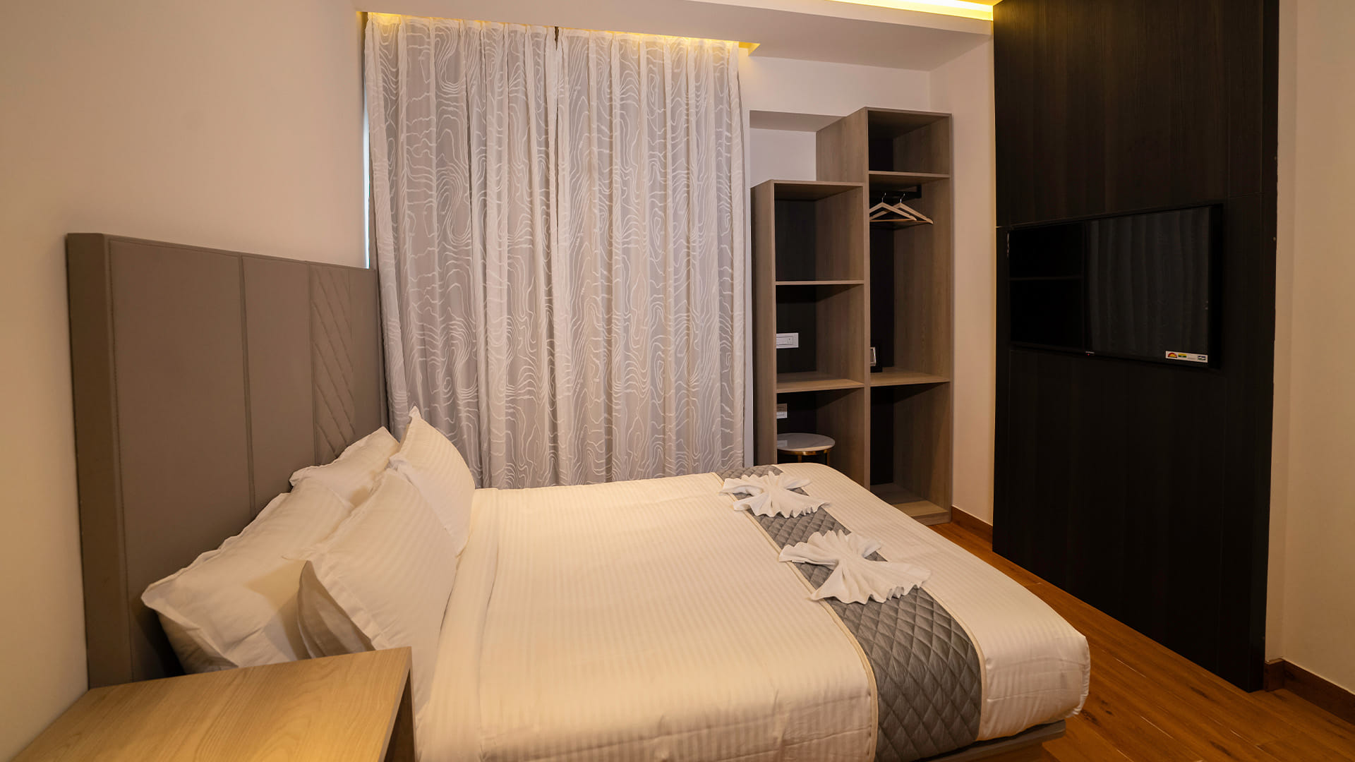 Classic Queen Room with a queen bed and a wall-mounted television beside an open wardrobe