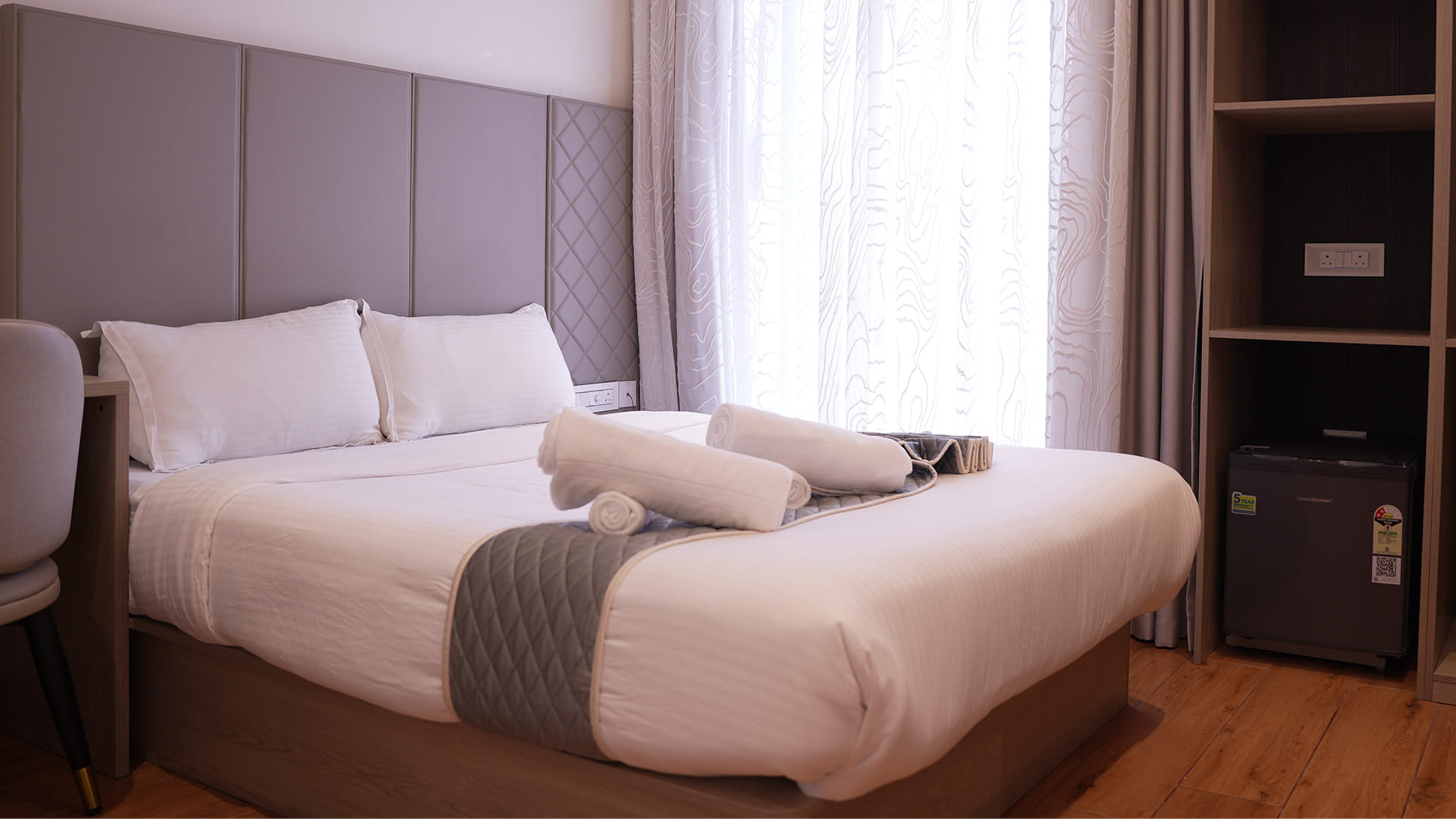 Classic Queen Room with a queen bed and open wardrobe shelving beside a mini fridge