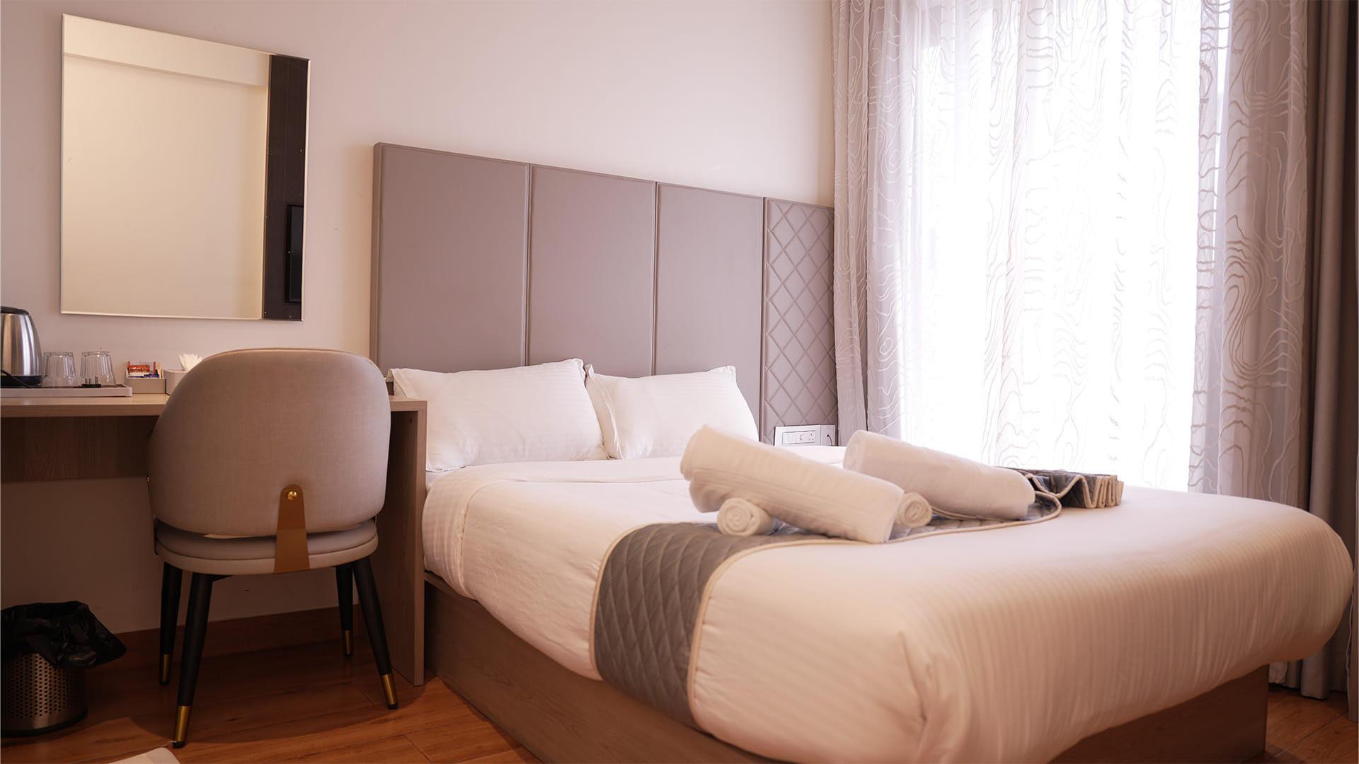 Classic Queen Room with a queen bed, a wall mirror above the desk, and rolled towels on the bedspread