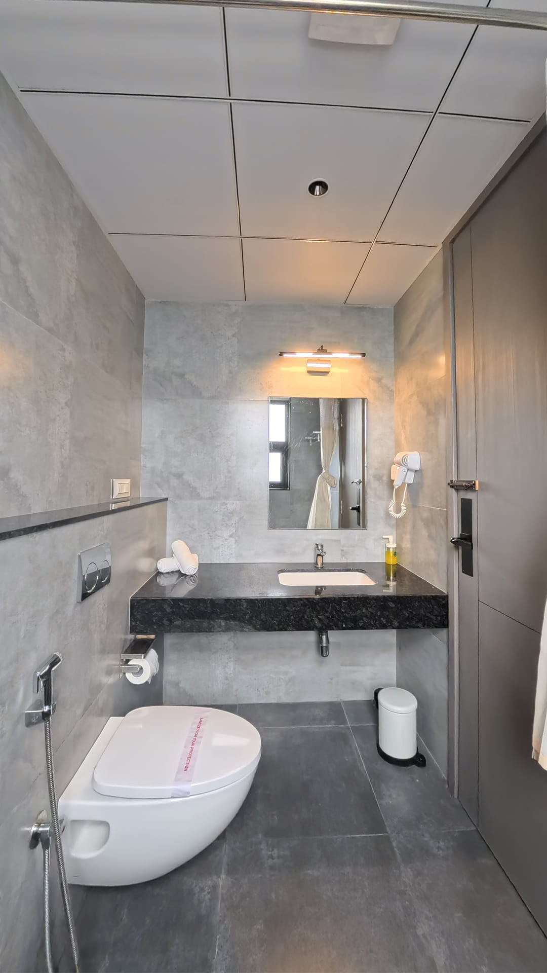 Bathroom with a black granite vanity, a mirror, and a wall-mounted toilet