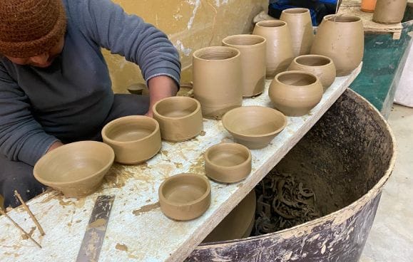 A potter shaping one of the hand-thrown clay bowls used for refillable bathroom amenities across guest rooms at Nepali Ghar Hotel's sustainability programme.