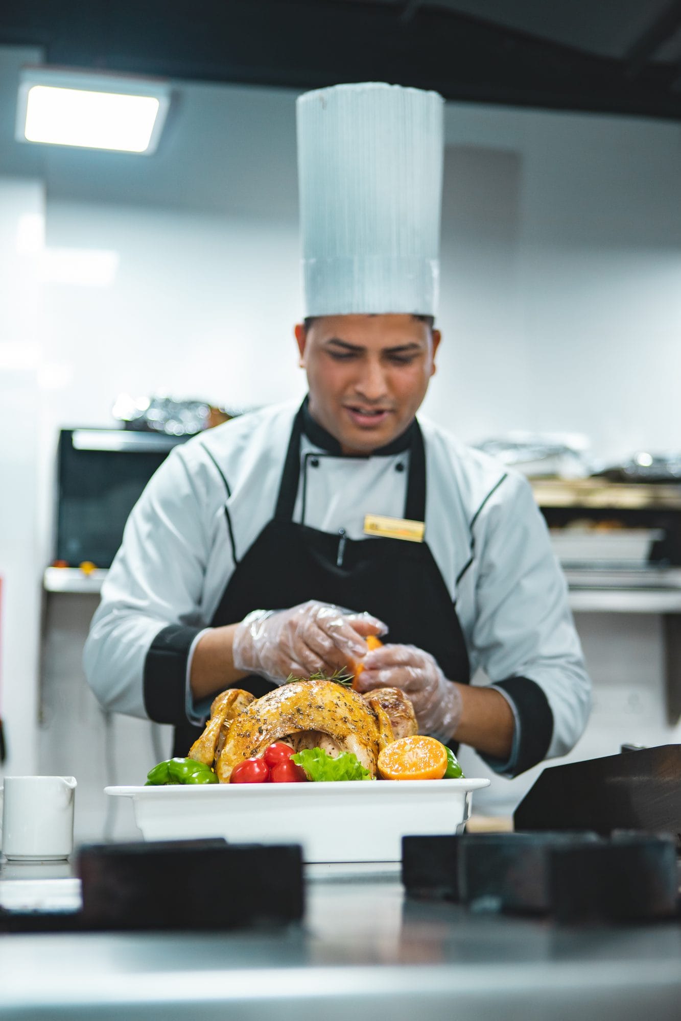 A chef plating a dish at the pass in the kitchen of Chiya Pasal restaurant, Nepali Ghar Hotel, adding the small finishing touches before it reaches the table.
