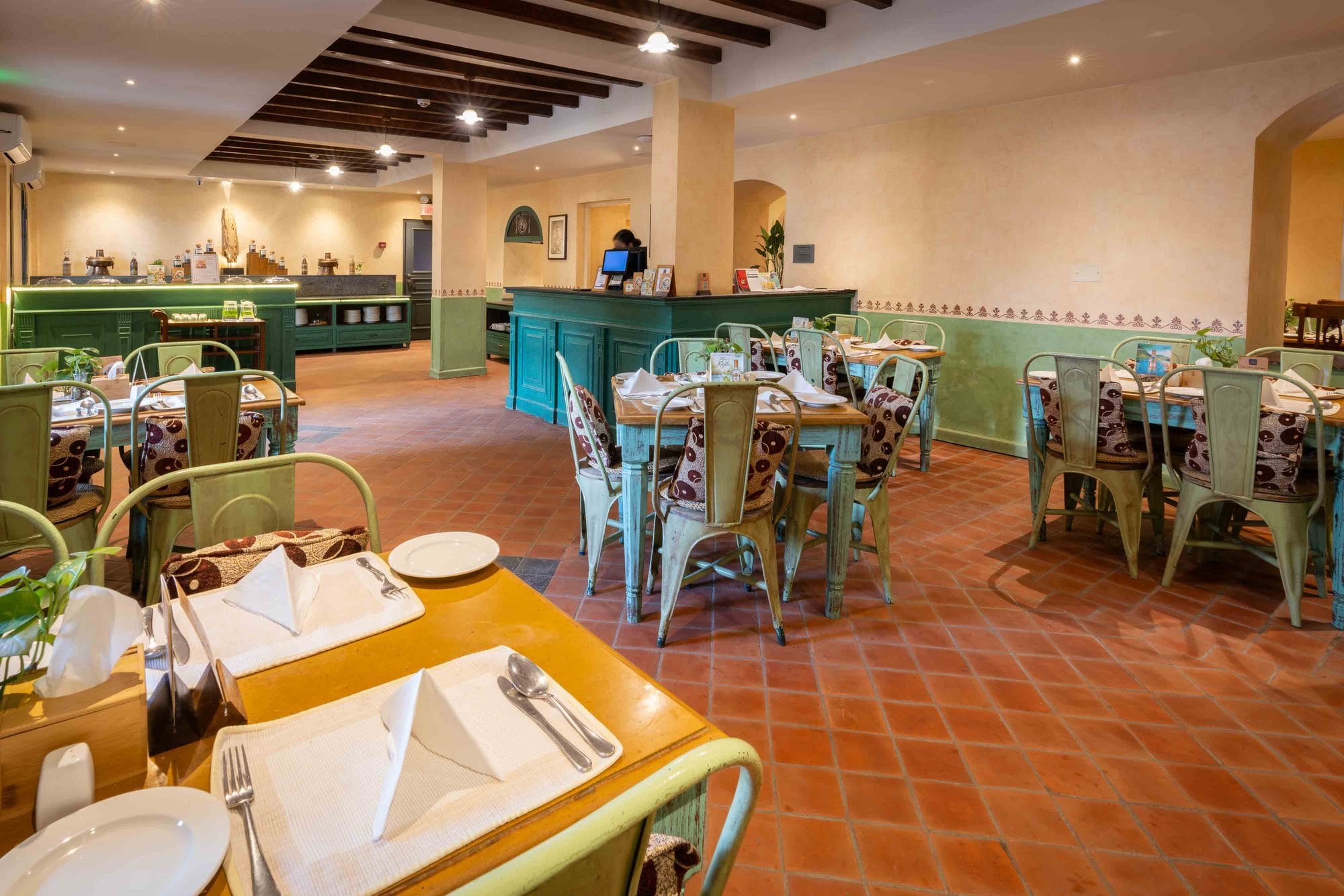 The colonial retro-style indoor dining room at Chiya Pasal, the all-day restaurant of Nepali Ghar Hotel, with terracotta floors and green timber furniture.