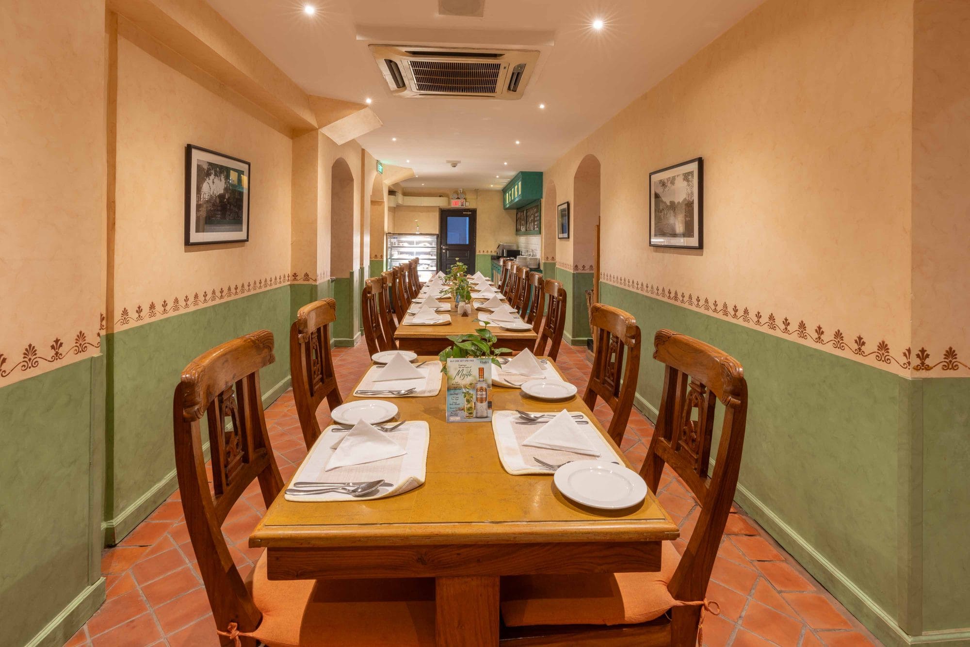 The inner dining area at Chiya Pasal restaurant, Nepali Ghar Hotel, set for a long table of guests beneath timber beams, away from the open front yard seating.