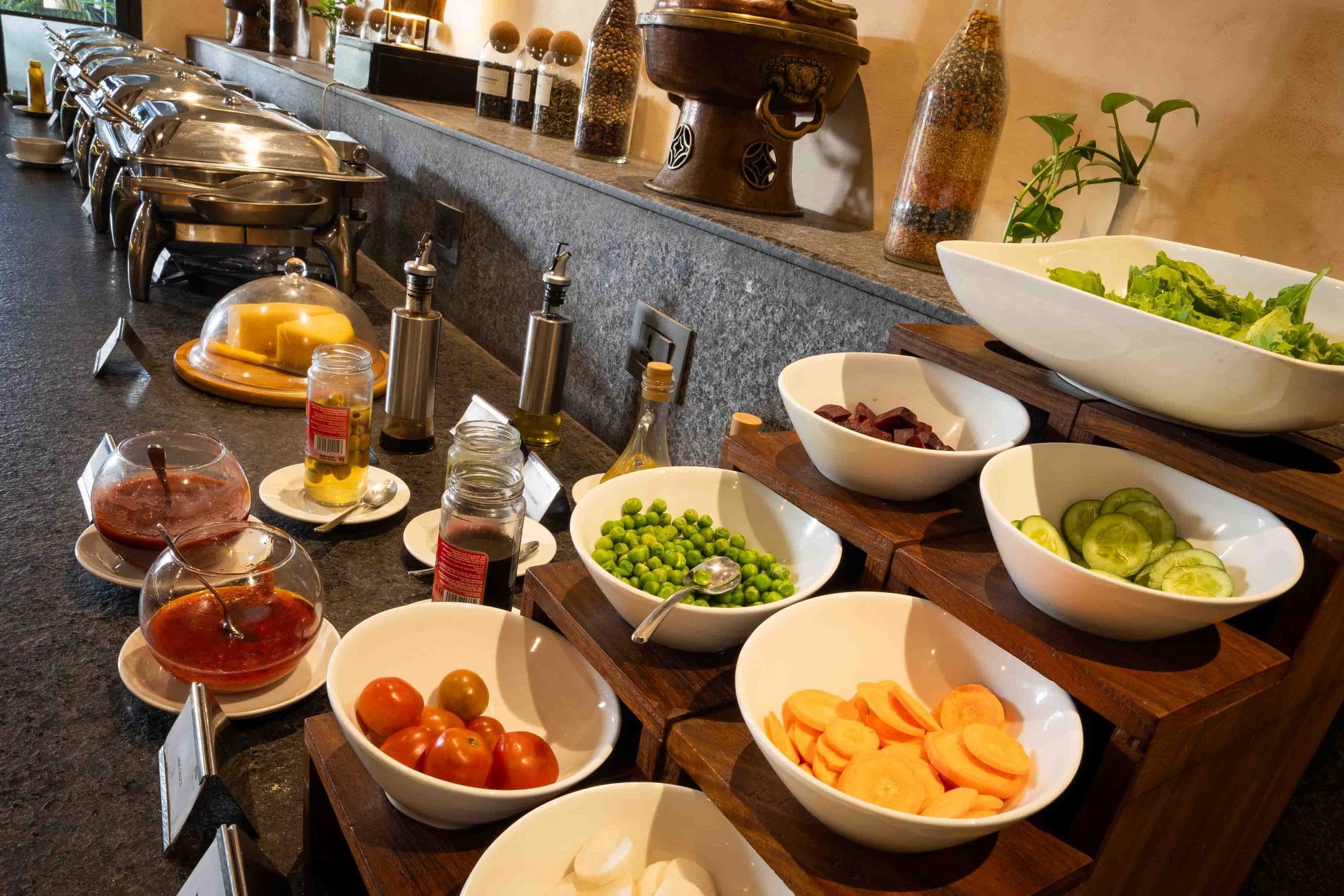 The salad and preserves spread at Chiya Pasal restaurant, Nepali Ghar Hotel, laid out with garden greens, tomatoes, and an assortment of house-made pickles.