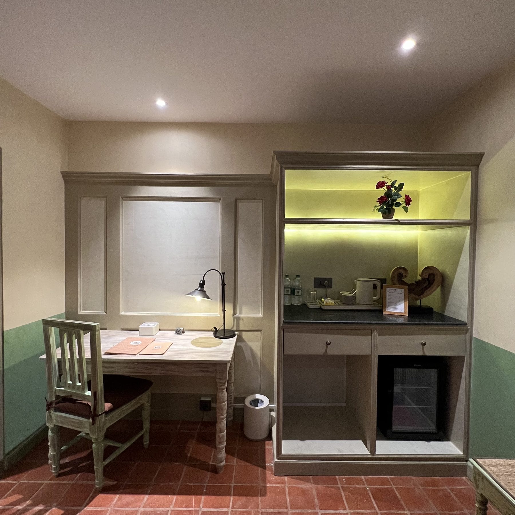The writing desk and minibar nook in the Classic Junior Suite at Nepali Ghar Hotel, fitted with coffee-making facilities beneath a large wall-mounted shelf.