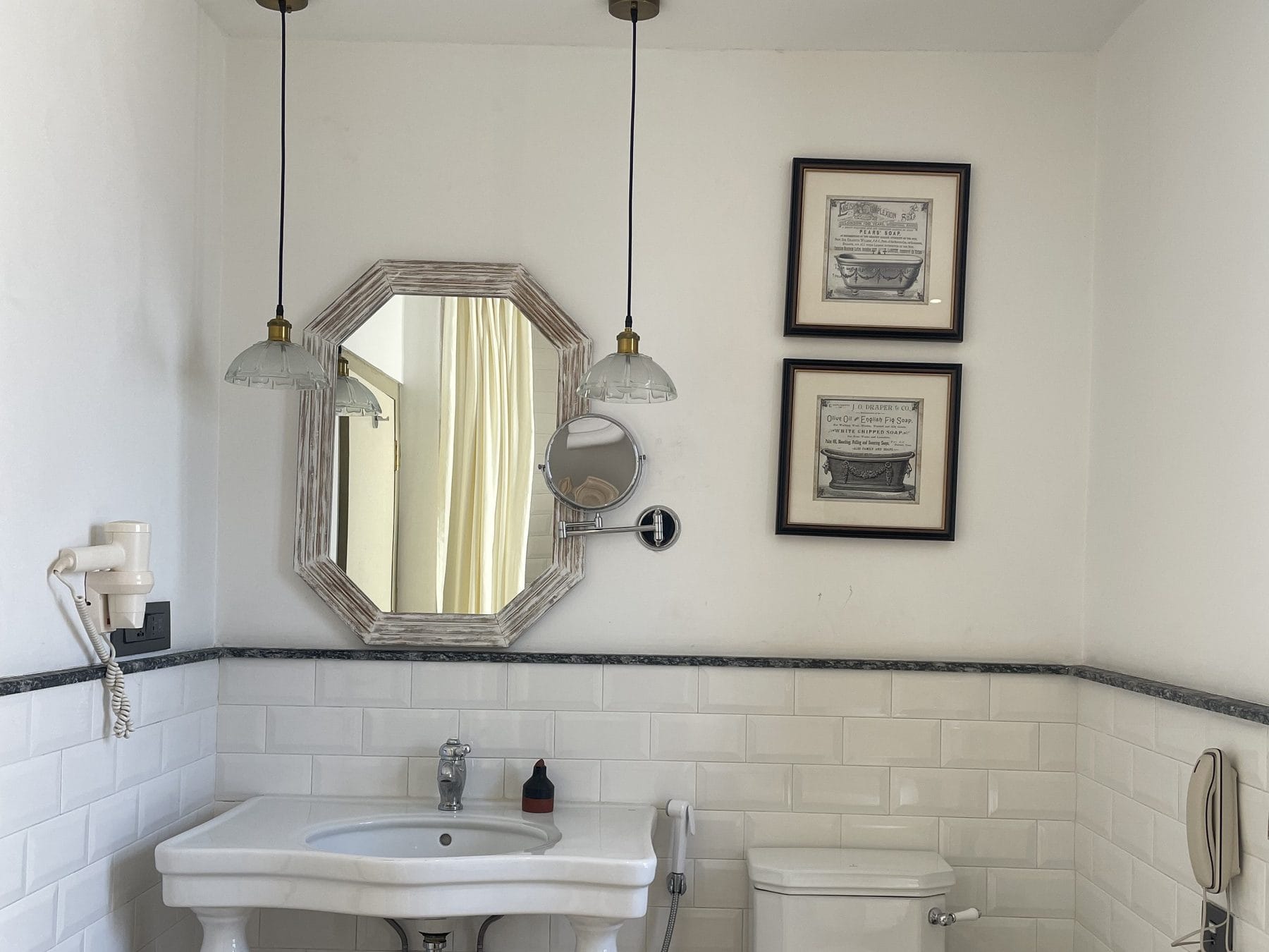 The bathroom vanity in the Classic Junior Suite at Nepali Ghar Hotel, with a marble washstand, an octagonal mirror, and brass fittings above the stone counter.