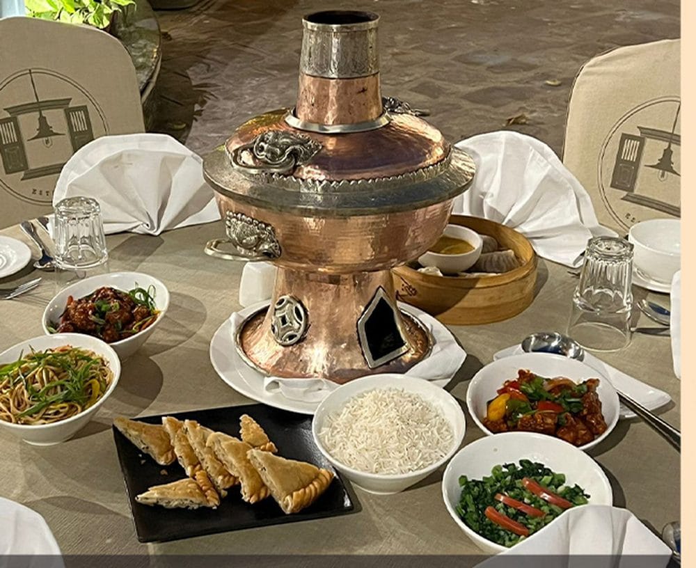 A tailor-made banquet menu spread at Nepali Ghar Hotel, featuring a traditional warm copper hotpot, steamed dumplings, rice, and an assortment of side dishes.