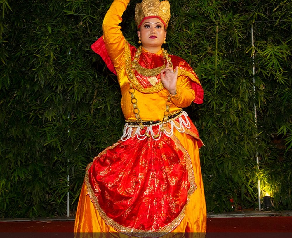A dancer in a colourful traditional Nepali costume performing a cultural show for guests at a private event hosted in the garden courtyard at Nepali Ghar Hotel.