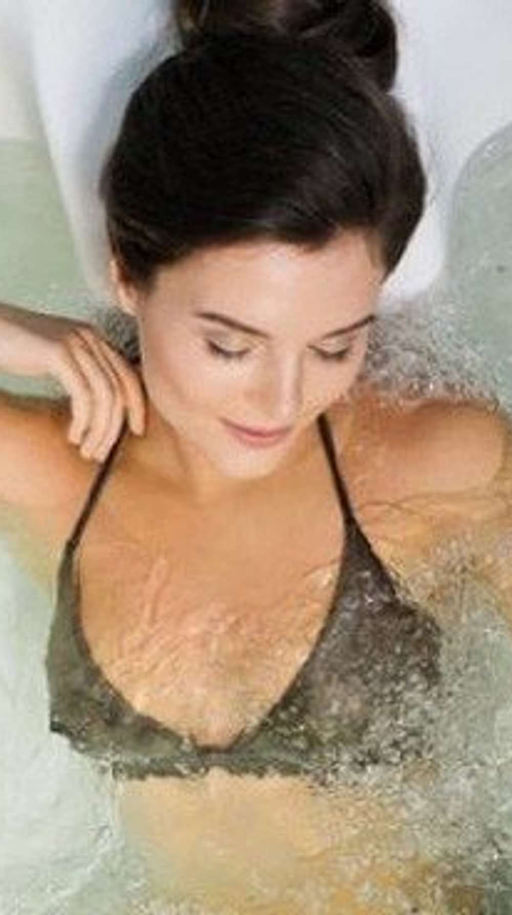 A woman enjoying a therapeutic water bath at YO1, Catskills, New York, designed to promote relaxation and wellness.
