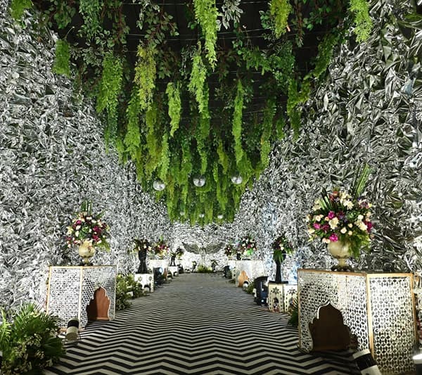 Banquet aisle with floral decor, hanging greenery and a zig-zag floor at Lime Tree Hotel & Banquet, Jaipur