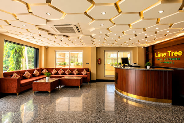 Lobby and reception desk with maroon sofas at Lime Tree Hotel & Banquet, Jaipur