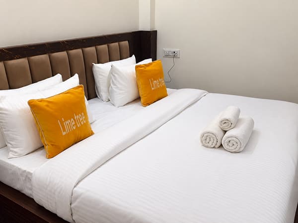 Deluxe Room king bed with an upholstered headboard at Lime Tree Hotel, Vrindavan