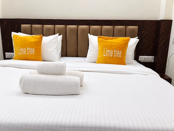 Deluxe Room king size bed with Lime Tree cushions and rolled towels at Lime Tree Hotel, Vrindavan