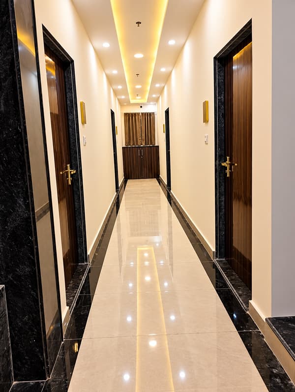 Guest corridor with a glossy tiled floor and ceiling lights at Lime Tree Hotel, Vrindavan