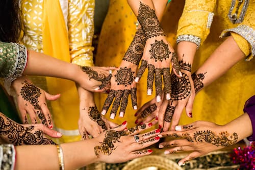 Intricate mehendi designs on guests' hands at a wedding celebration, Hotel Aarna Premier, Jaipur