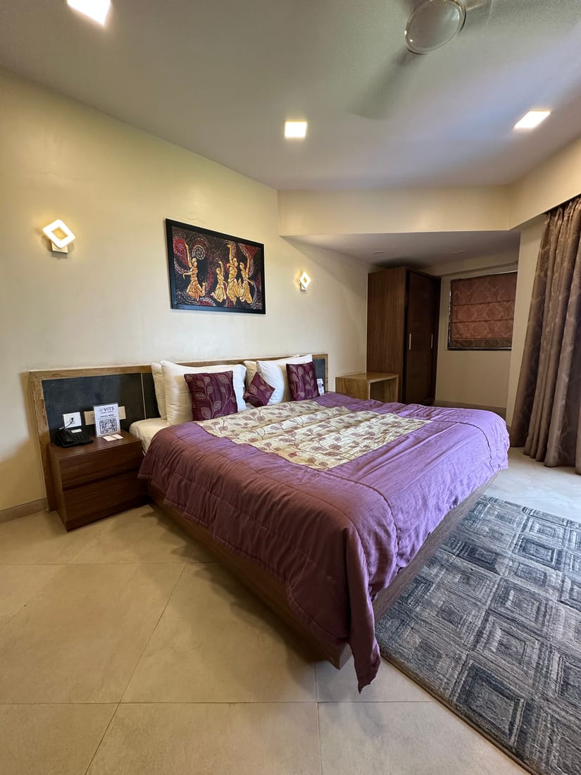 King-size bed with purple bedding in a room at VITS Kamats Resort Silvassa