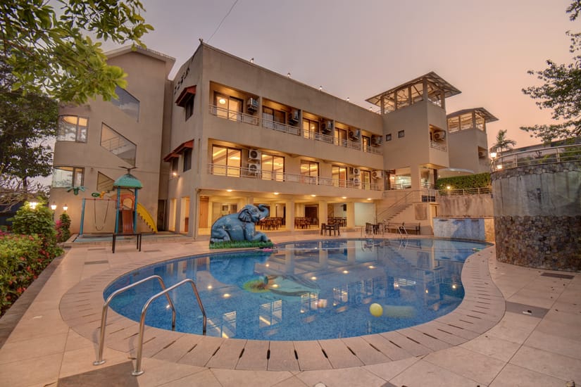 Swimming pool in front of the hotel facade at dusk at VITS Lonavala