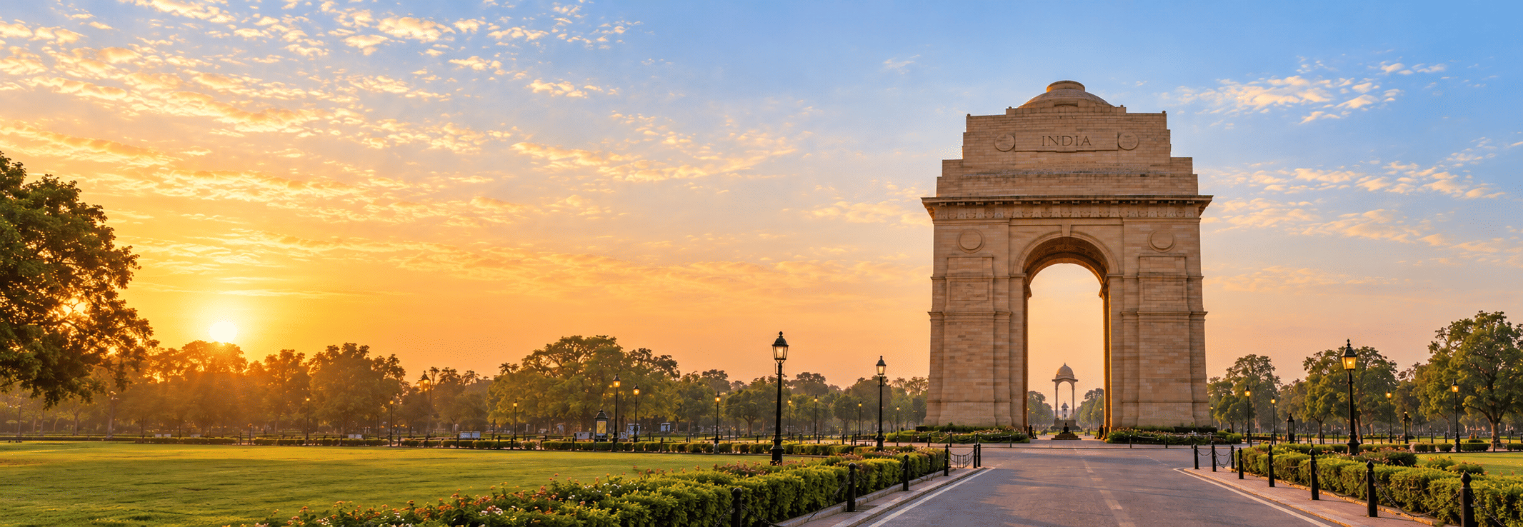 India Gate at sunrise, the sun rising through the trees along Kartavya Path