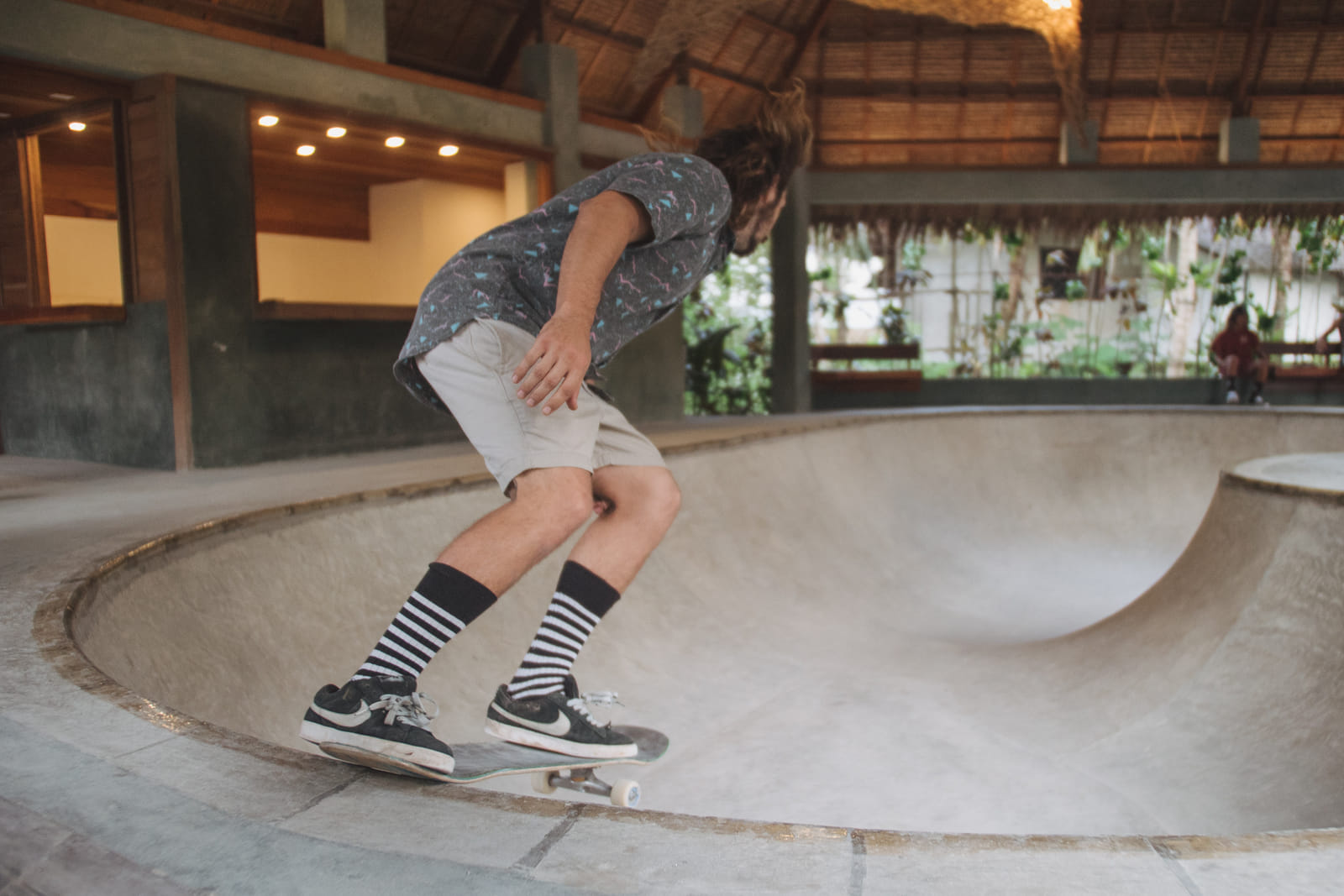 A skater in striped socks balancing on a skateboard at the edge of the concrete bowl at the Bravo Skate Bowl, Bravo Beach Resort Siargao