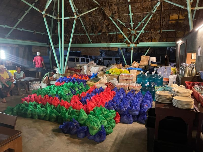 Rows of colorful green, red, and blue relief goods bags organized on the floor at Bravo Beach Resort Siargao during a community relief operation
