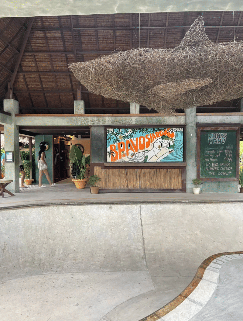 Bravo Beach Resort Siargao skate bowl area with a woven shark sculpture overhead, a BravoSiargao mural sign, and drinks menu board