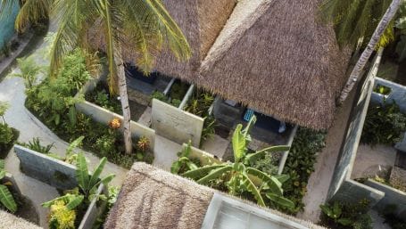 Aerial view of thatched-roof villas at Bravo Beach Resort Siargao, each with private walled gardens, palm trees, and tropical plants