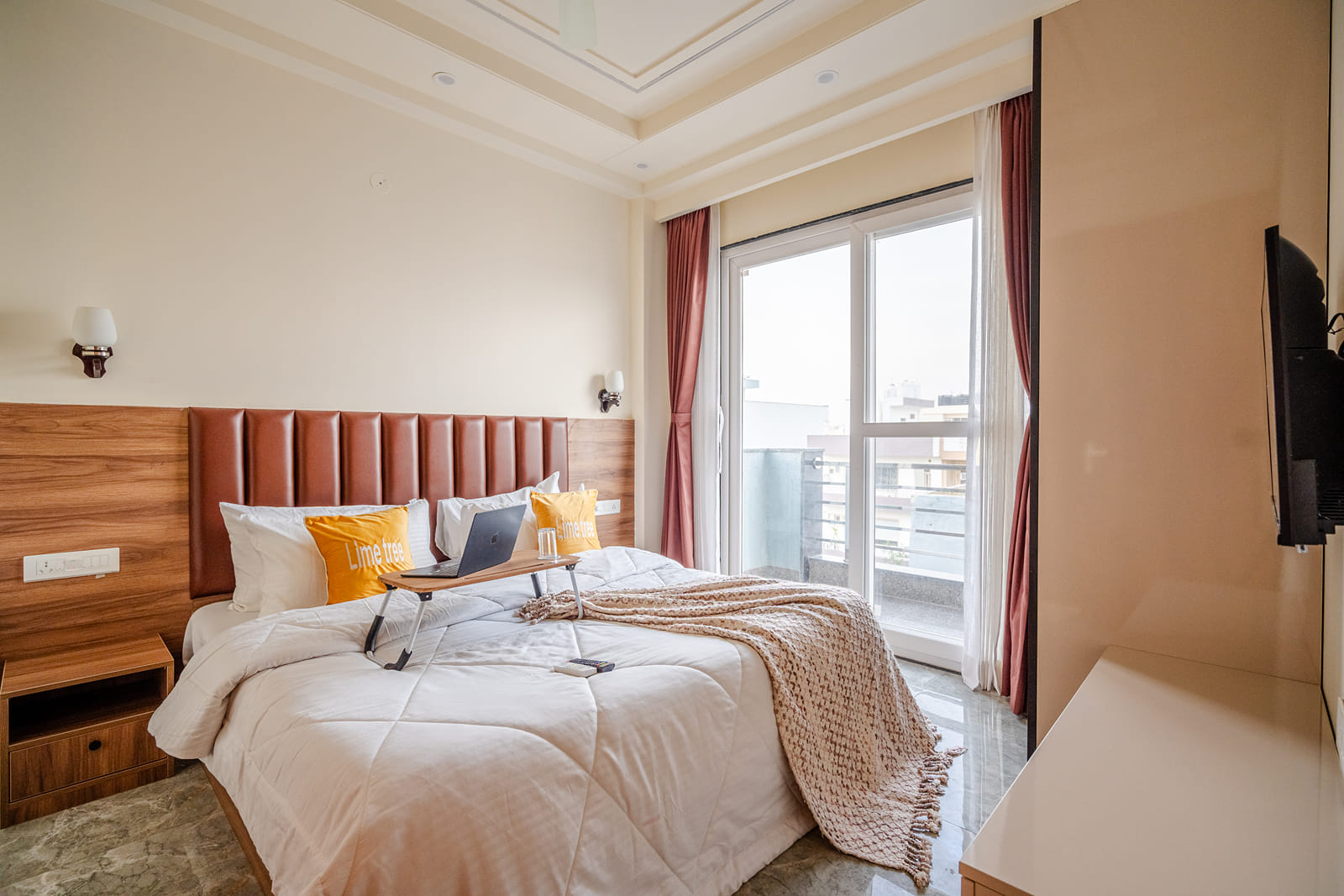 Bedroom with a double bed, cushioned headboard and balcony door at Lime Tree 1BHK Service Apartment Near Artemis Hospital