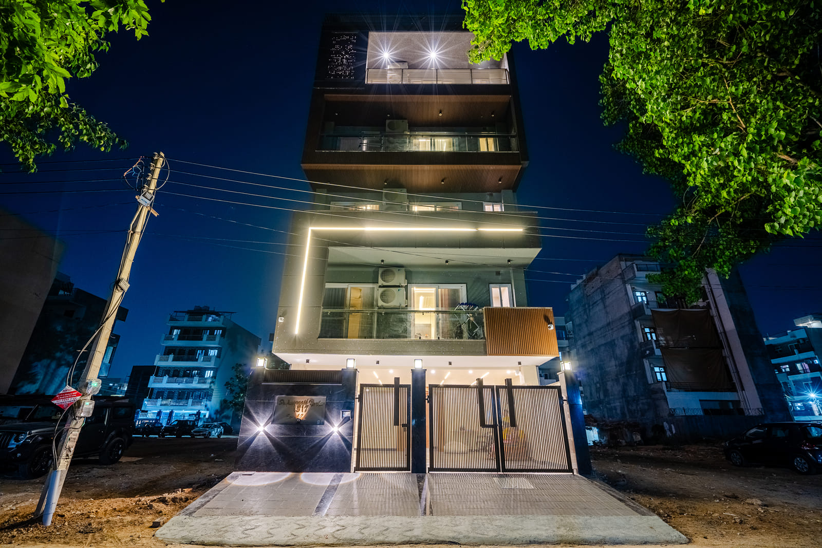 Multi-storey building lit up at night with a gated entrance at Lime Tree 1BHK Service Apartment Near Artemis Hospital