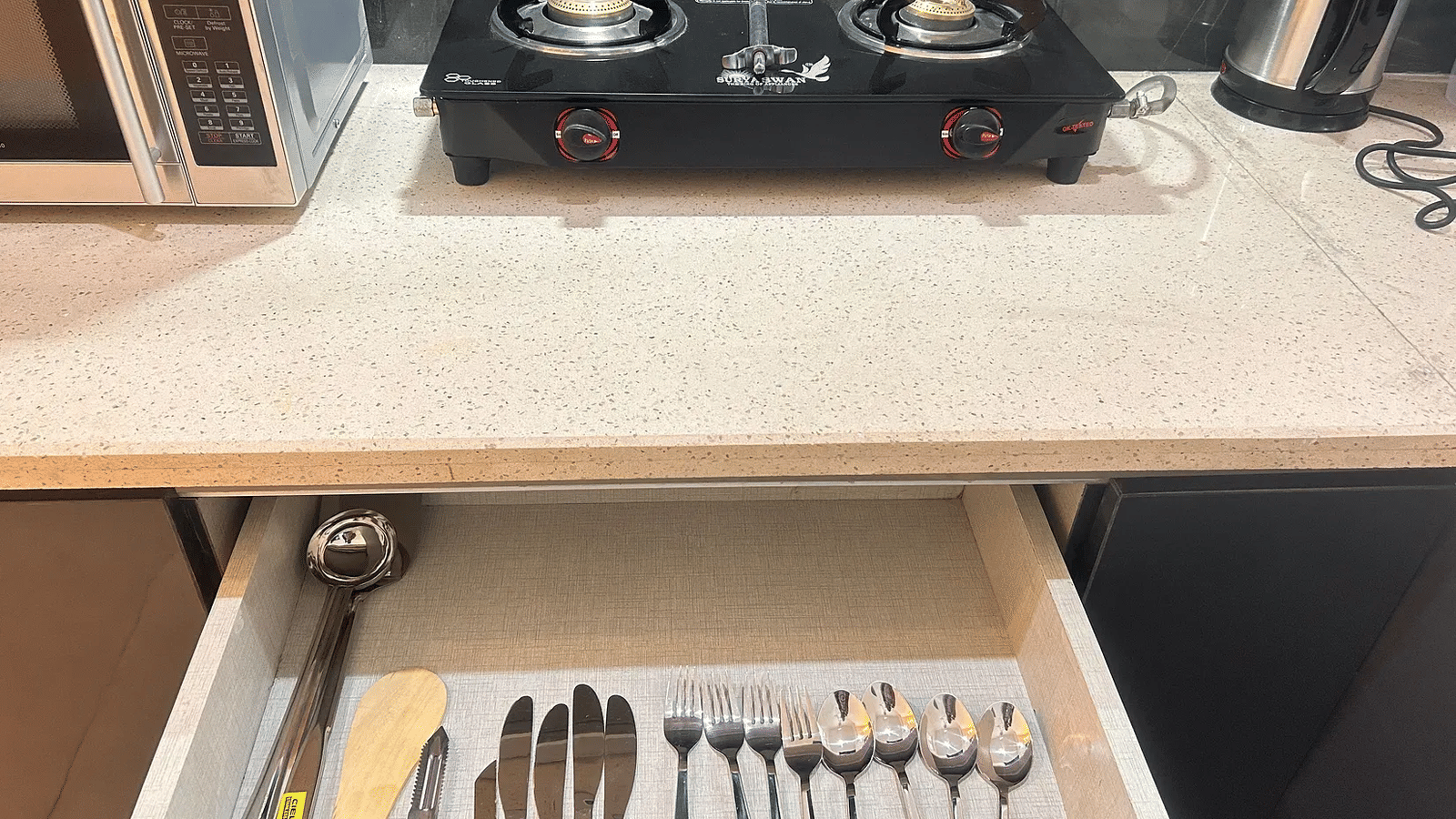 Kitchen counter with gas stove and open cutlery drawer at Lime Tree 1BHK Serviced Apartment Near Medanta
