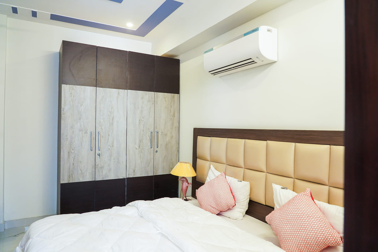 Bedroom with a cushioned headboard, wardrobe and air conditioner at Lime Tree 2BHK Serviced Apartment Near Artemis