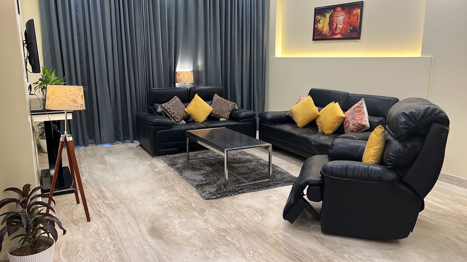 Living room with black leather sofas and a glass coffee table at Lime Tree 3BHK Serviced Apartments, DLF Phase-5