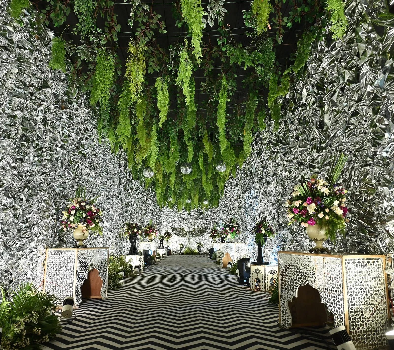 Banquet aisle with floral decor, hanging greenery and a zig-zag floor at Lime Tree Hotel & Banquet, Jaipur
