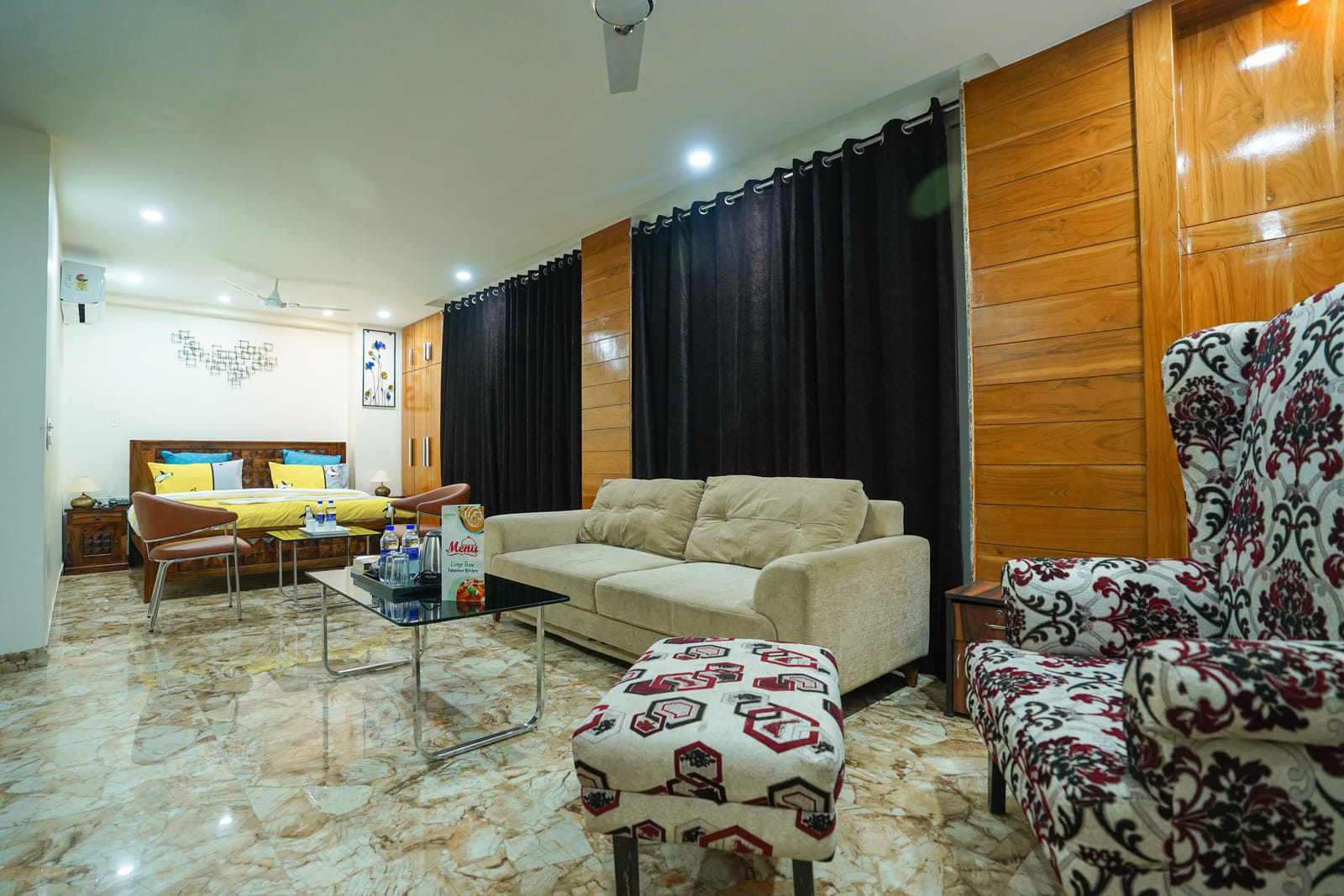 Spacious room with a bed, beige sofa, patterned armchair and glass coffee table at Lime Tree Hotel Near 32nd Avenue