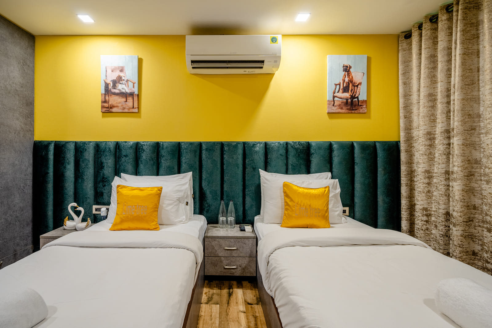 Twin beds with a teal padded headboard and yellow accent wall at Lime Tree Hotel Near Medanta–The Medicity