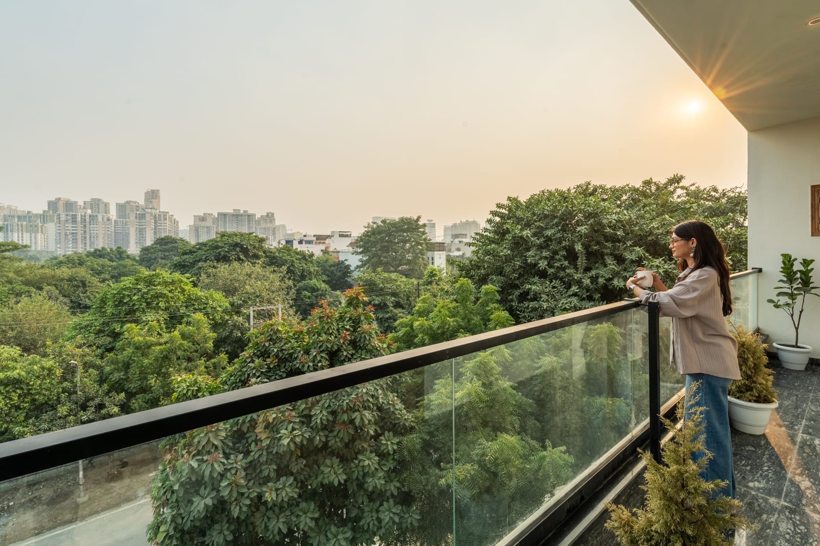 Balcony with a glass railing and green tree views at Lime Tree Hotel and 1BHK Serviced Apartment, Noida