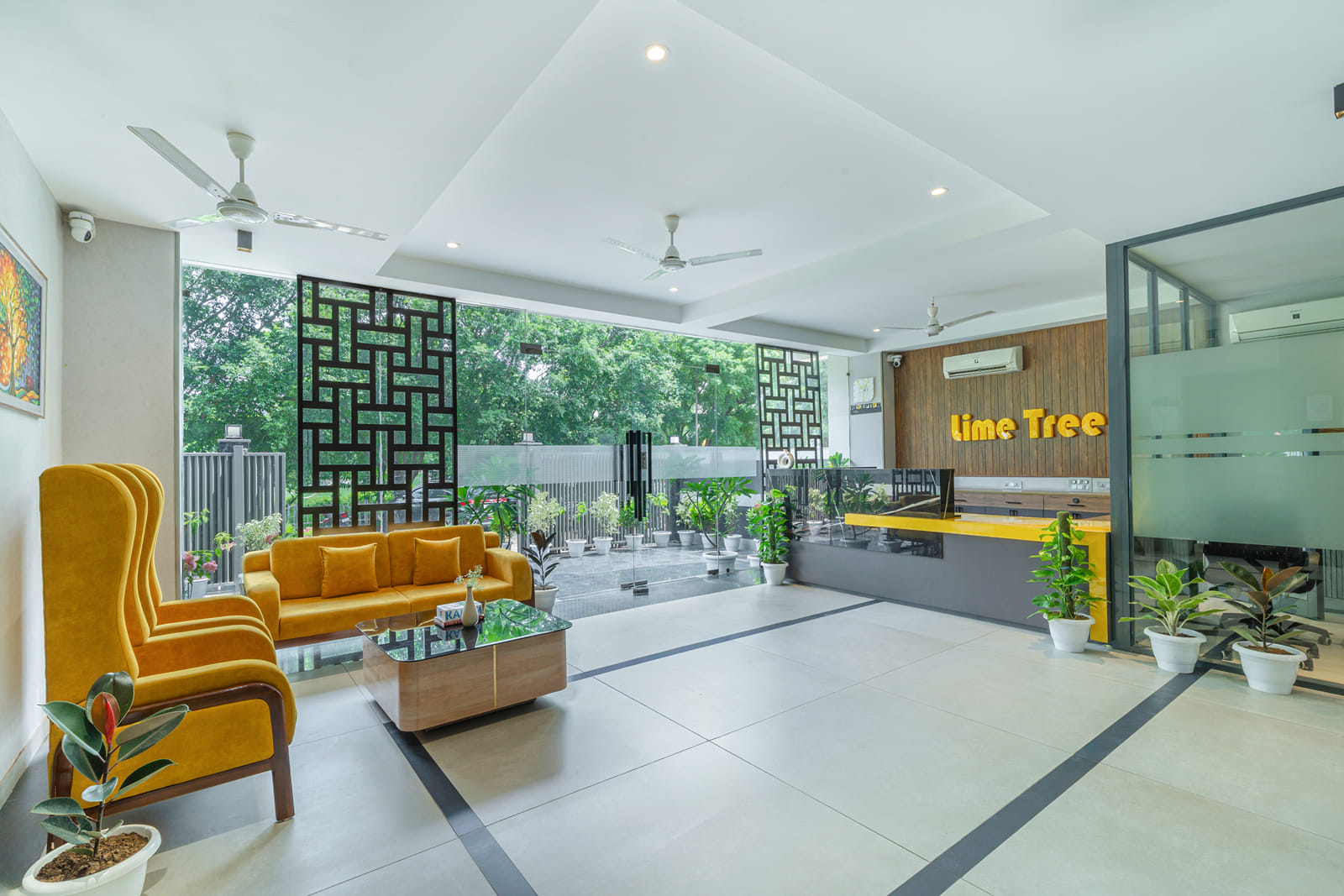 Bright lobby with yellow sofa seating, reception counter and garden view at Y Stay by Lime Tree Hotels, Greater Noida