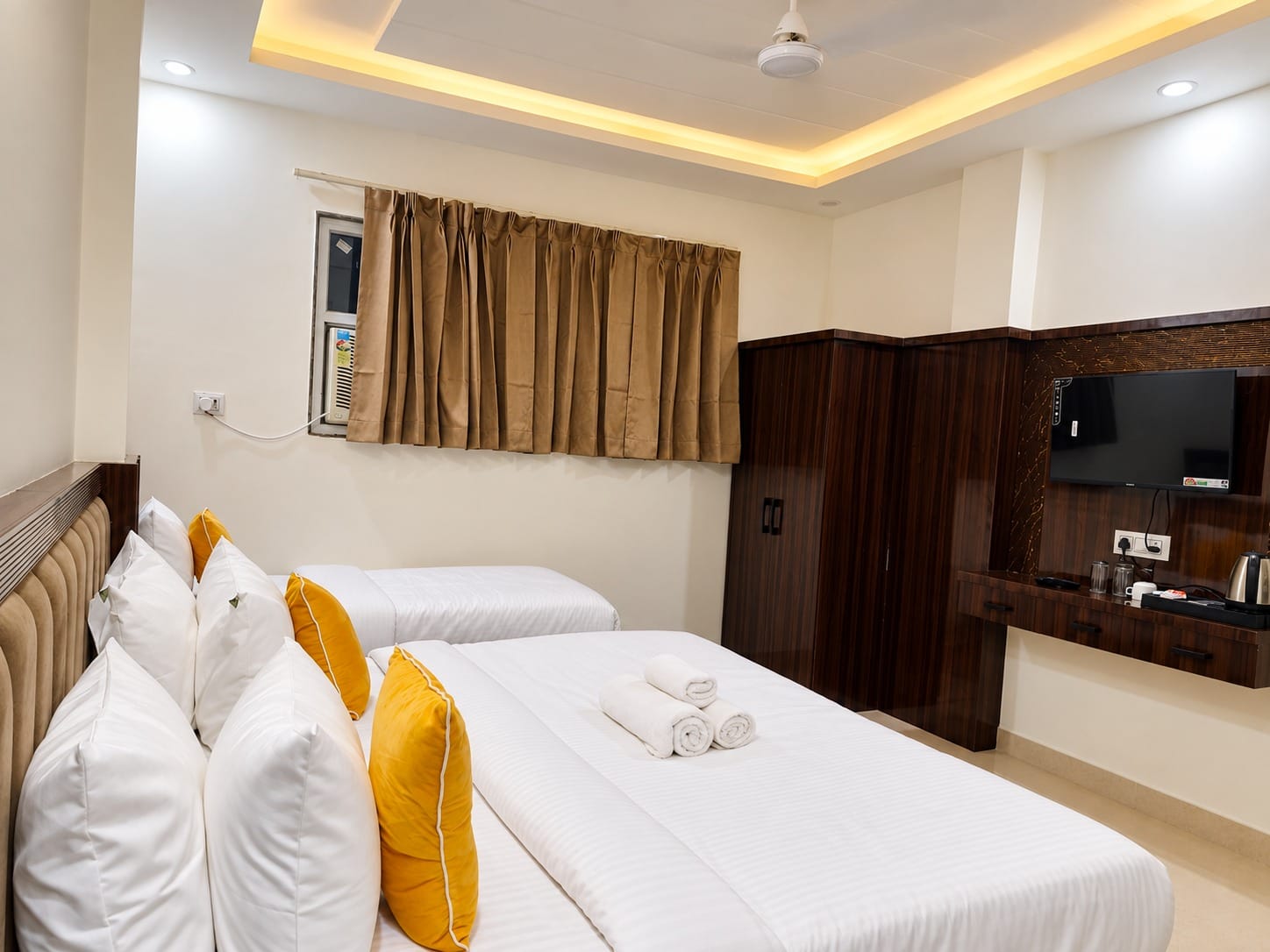 Deluxe Room bed with white linen and yellow cushions at Lime Tree Hotel, Vrindavan