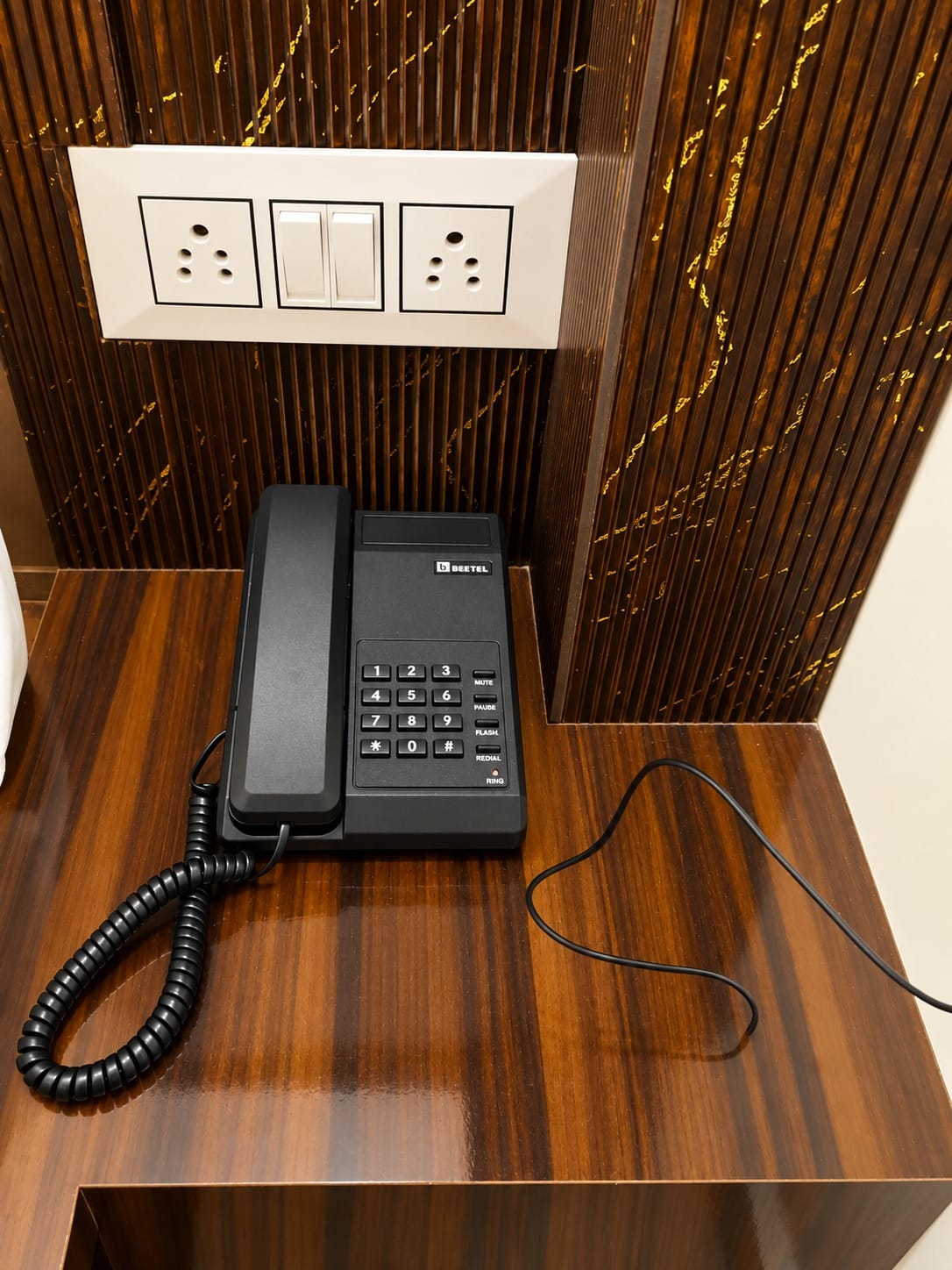 Telephone on a wooden bedside table at Lime Tree Hotel, Vrindavan