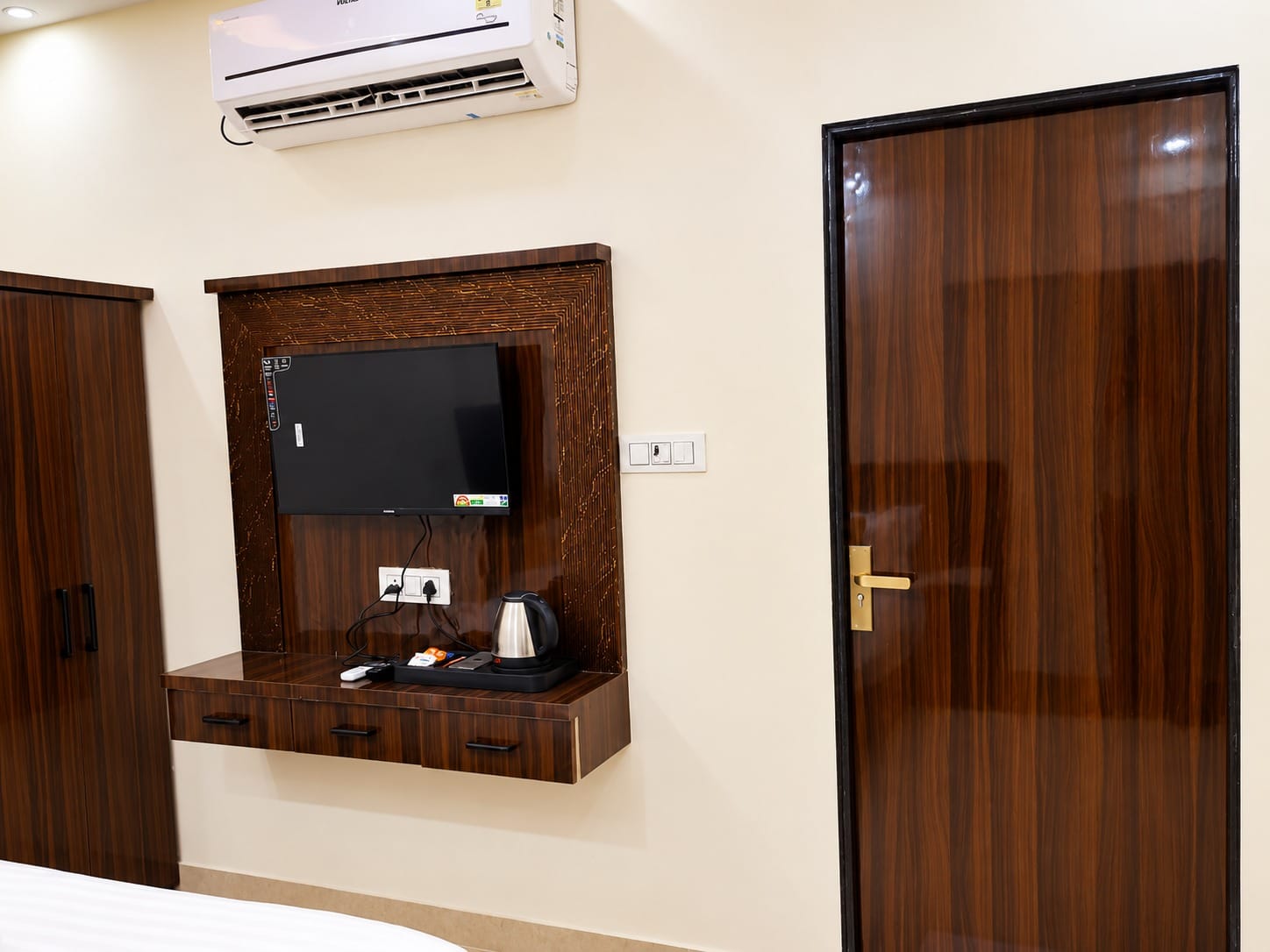 Deluxe Room TV unit with a kettle beside the door at Lime Tree Hotel, Vrindavan