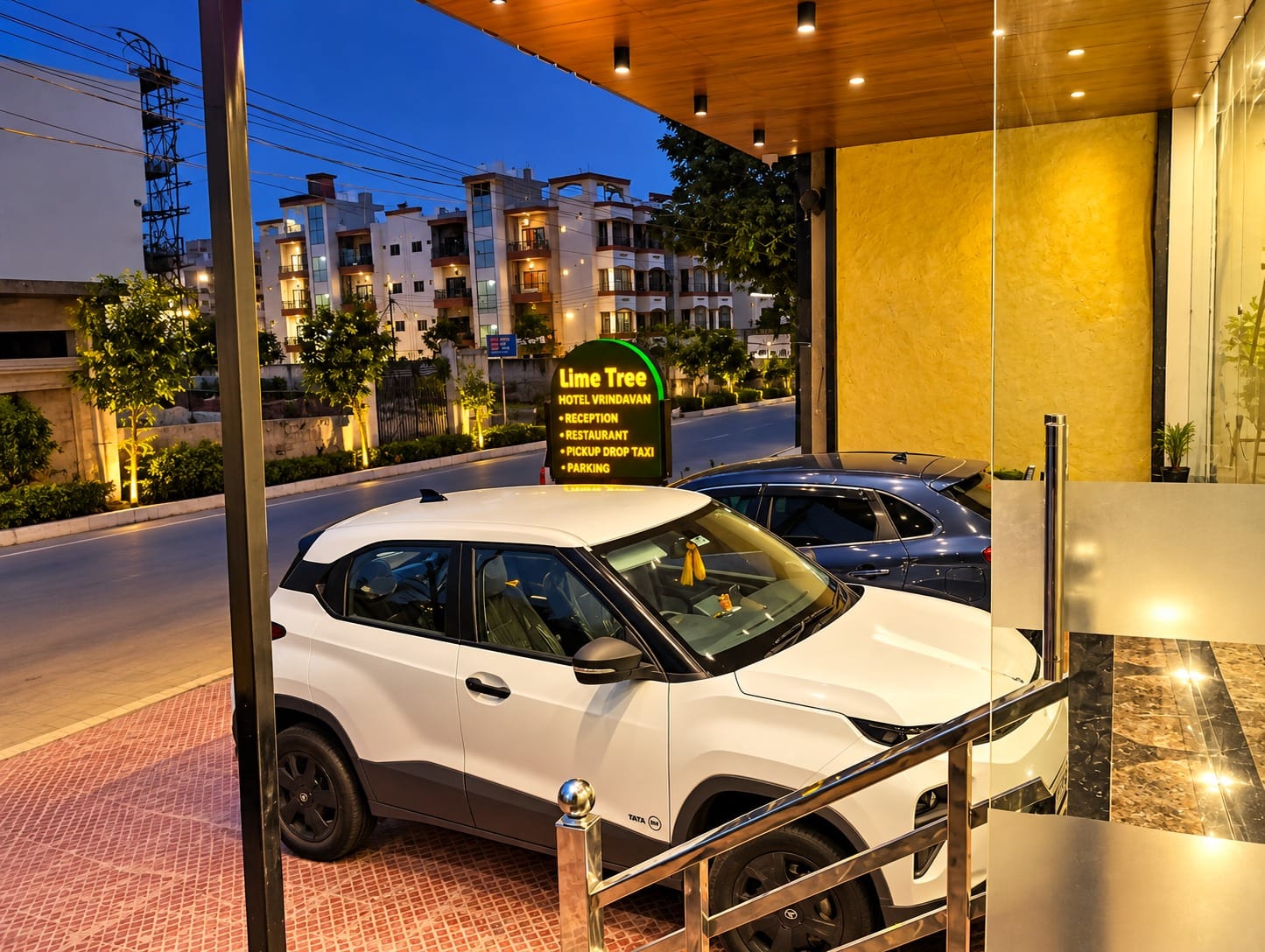 Car at the lit-up entrance of Lime Tree Hotel, Vrindavan at dusk