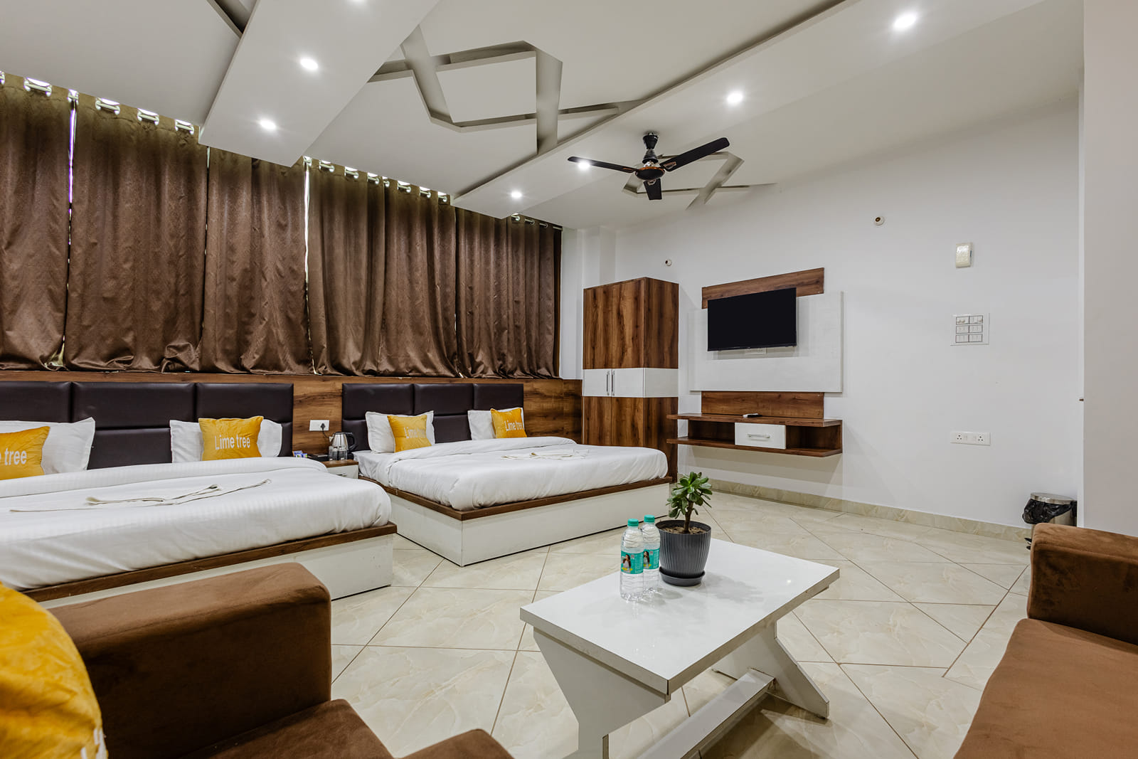 Large room with two beds, brown curtains, a sofa and wall-mounted TV at Lime Tree Hotels and Banquet, Vrindavan