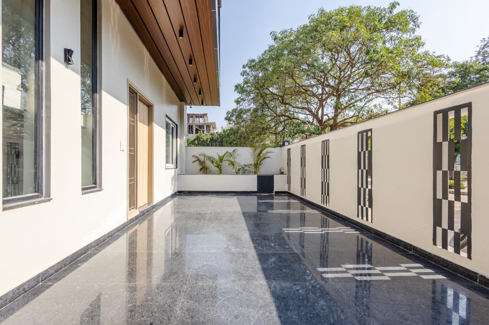 Glossy tiled outdoor corridor with a decorative screen wall and trees at Lime Tree Villa Vista Near Pari Chowk