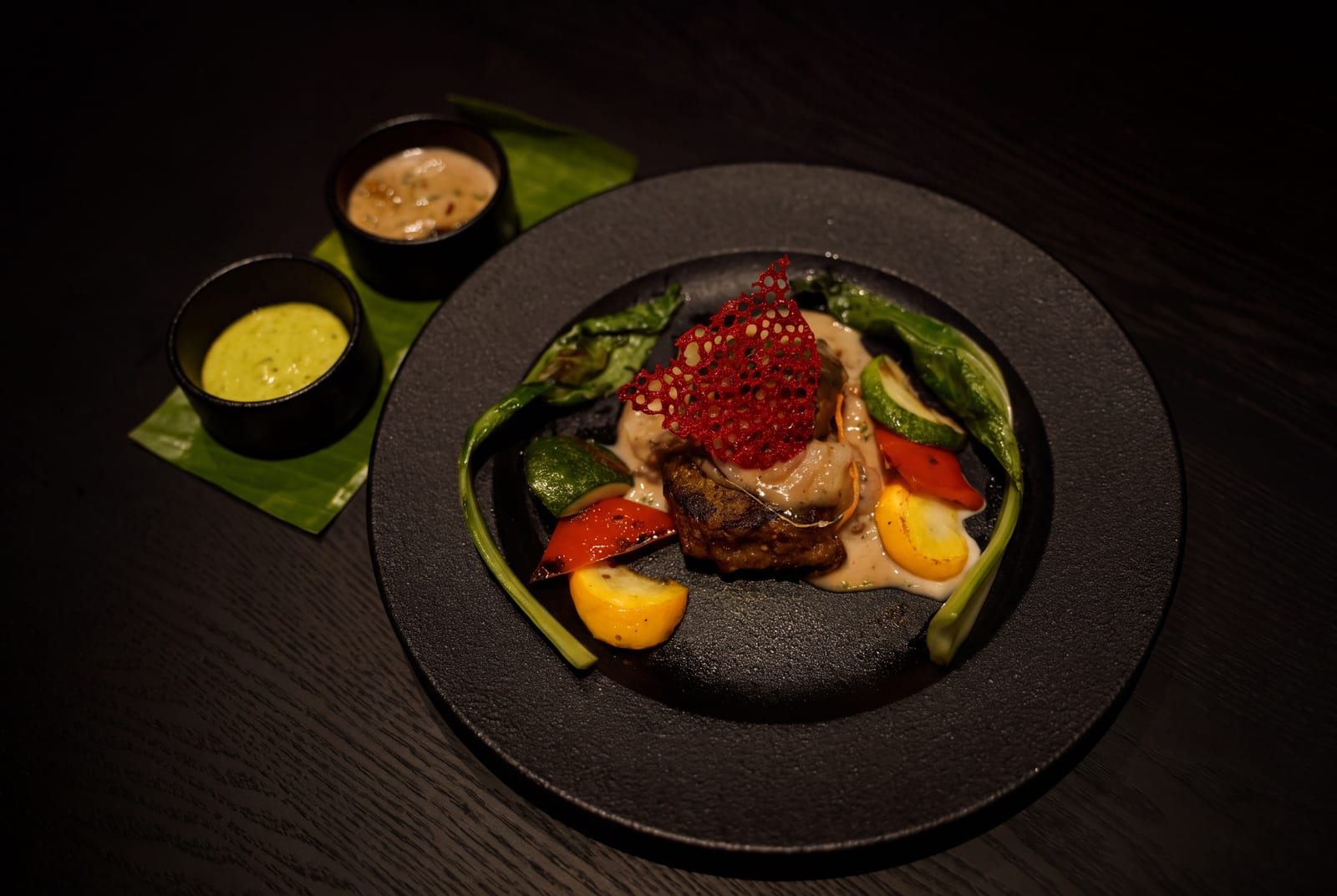 Plated dish topped with red garnish and vegetables, with two dips on a banana leaf at Azul Lounge & Bar, RG Grand Hotel & Convention.