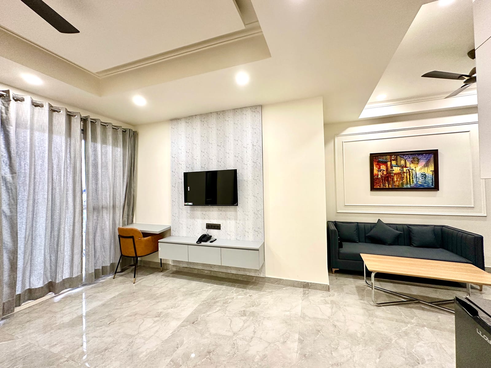 Living area with a wall-mounted TV, black sofa, coffee table and work desk at Street Studio by Lime Tree Hotels