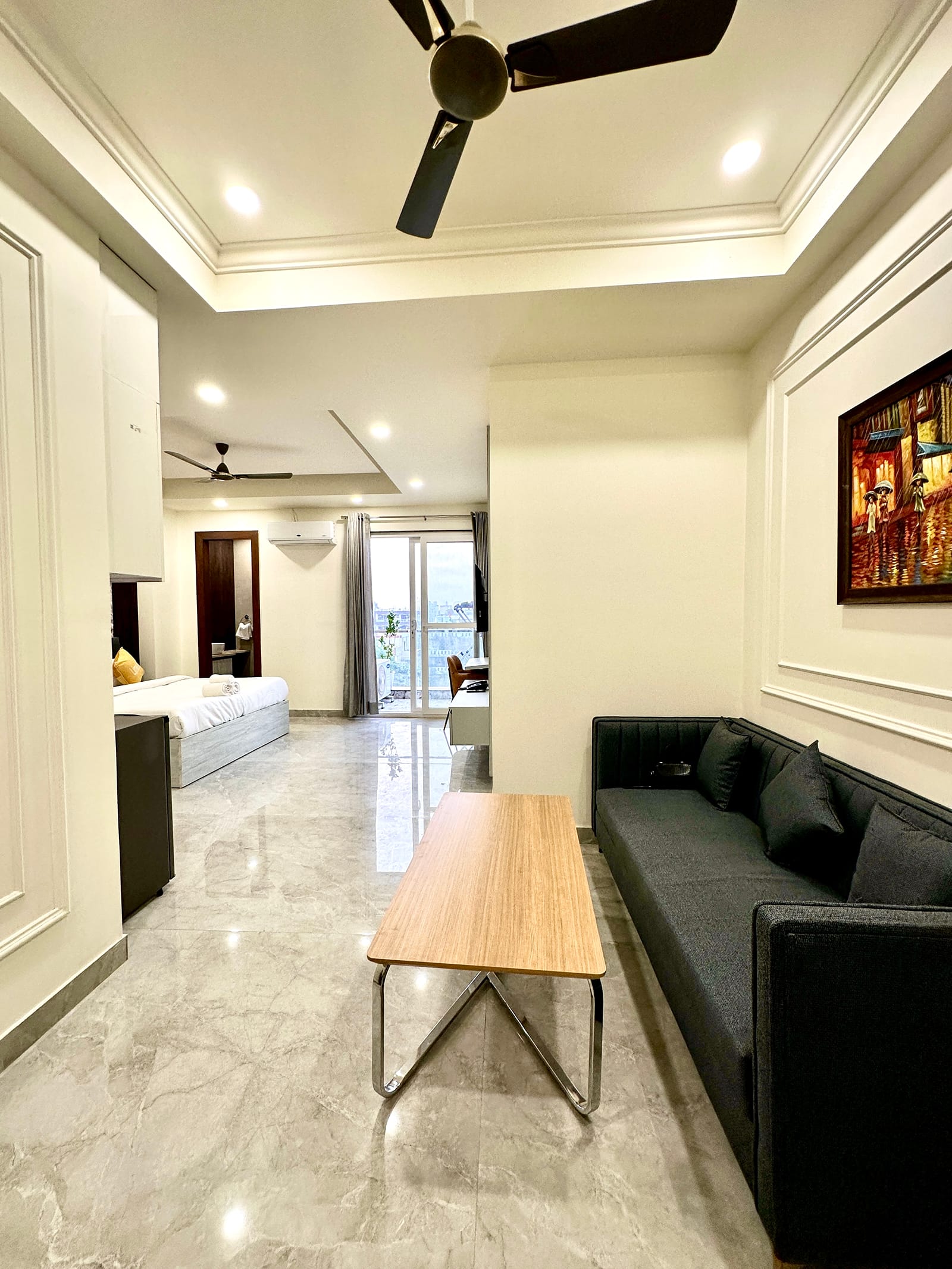 Studio with a grey sofa, coffee table and bed beside the balcony door at Street Studio by Lime Tree Hotels